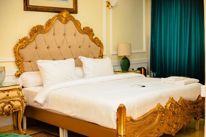 Chambre avec lit doré et rideaux émeraude